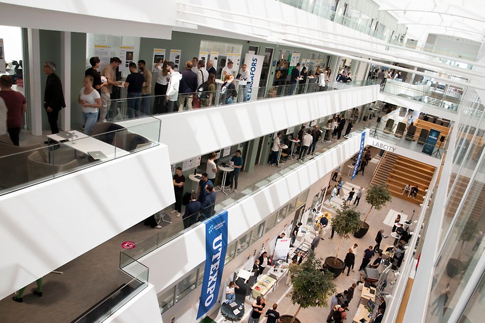 A large open space with people milling about. The space is divided by several floors. Photo.