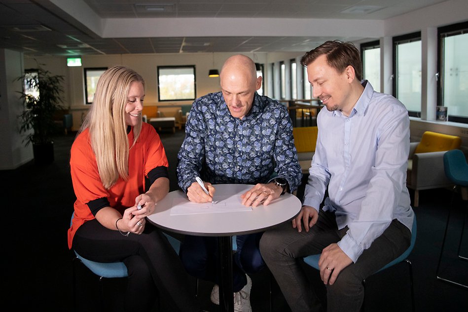 Three people sitting around a table.