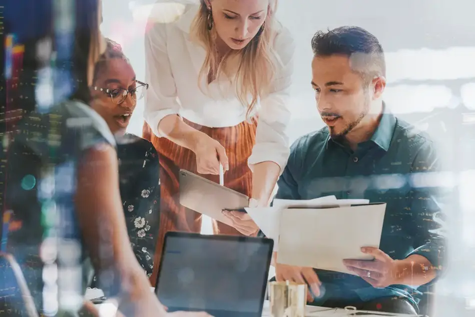En grupp människor som står runt en bärbar dator.
