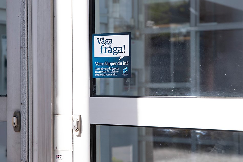Sticker on the front door with the text ‘dare to ask’ in Swedish. Photo.