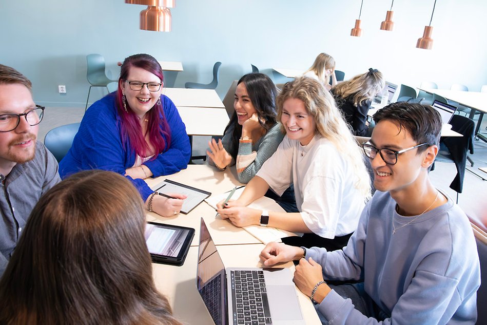 A group of students sitting around a table and laughing. Photo.