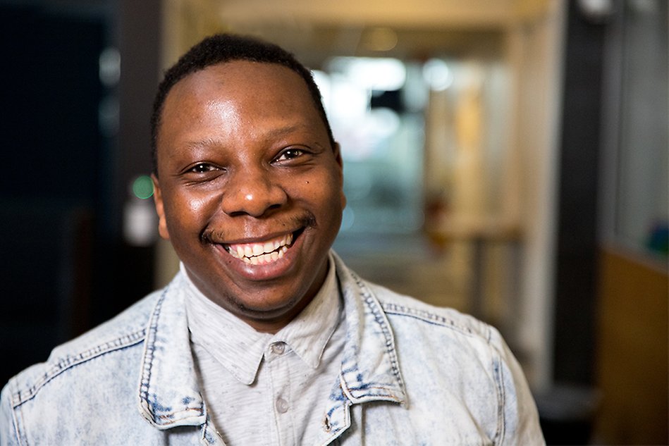 A portrait of a male student who smiles as he stands in the corridor in the Digital Laboratory Centre. 