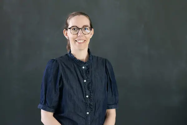 Person med glasögon som ler.
