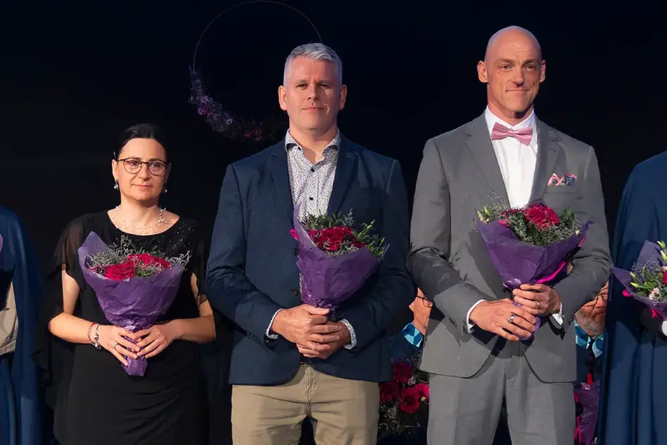 Tre personer står med blombukett i händerna och tittar in i kameran.