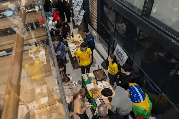 Översikt av människor vid bord i en öppen lokal. Flaggor och mat syns ihop med människorna.