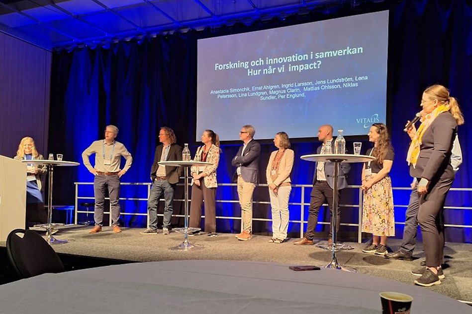 People are standing in front of a presentation, a panel-discussion.