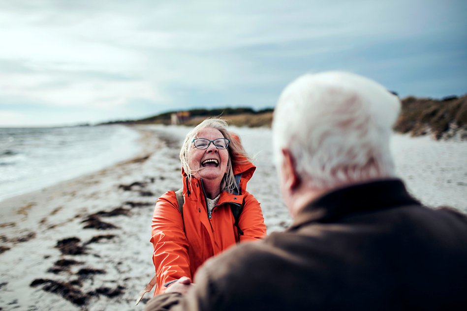 En man och en kvinna som håller varandra i handen på en strand.