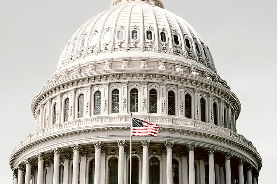 Kupolen på Kapitolium i Wahington DC med USA:s flagga i förgrunden. Foto
