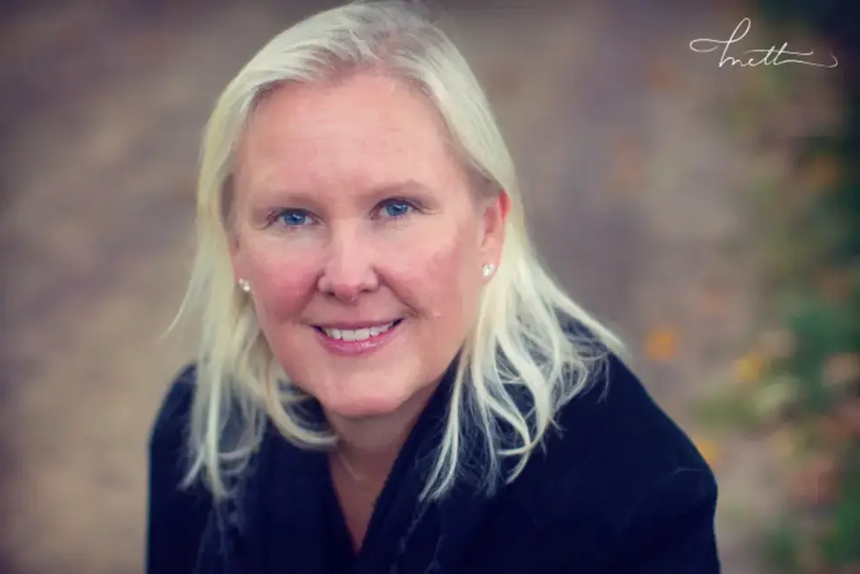 Portrait image of person with blond hair seen from above looking into the camera. Photo.