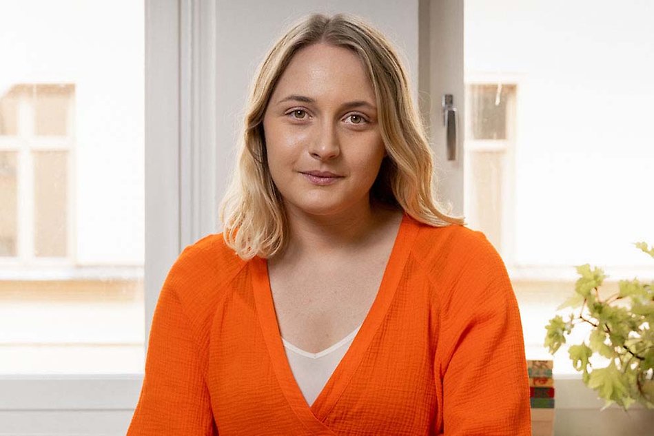 Ung blond kvinna med röd tröja tittar rakt in i kameran