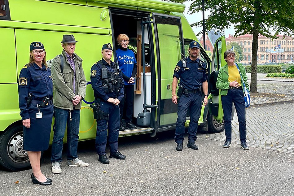 Sex personer, tre kvinnor och tre män, står framför en grön buss. Tre av personerna är klädda i polisuniform. Foto