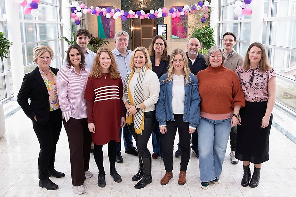 A group of happy people are standing together, smiling at the camera. 