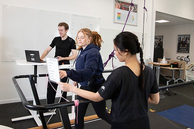 En student springer på ett löpband och två andra övervakar