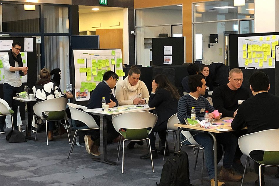 Groups of people working around tables.