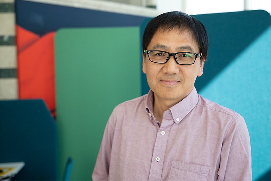 A man with dark hair and glasses looking in the camera. Photo.