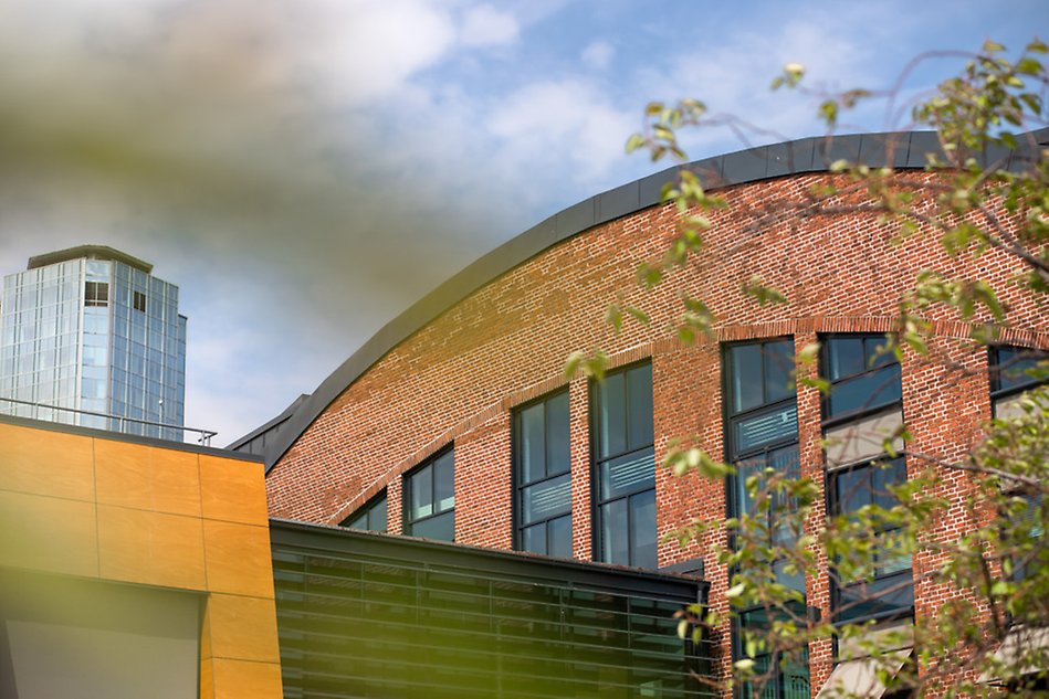 Large brick building in the foreground and a skyscraper in the background. 