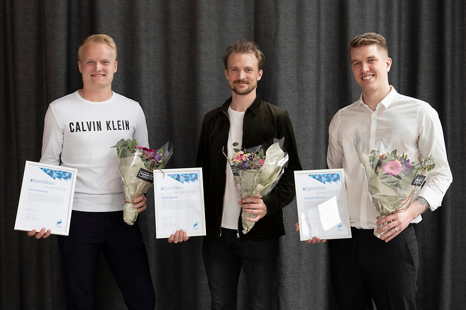 Tre manliga studenter mot grå bakgrund håller leende varsitt stipendium samt varsin blombukett.