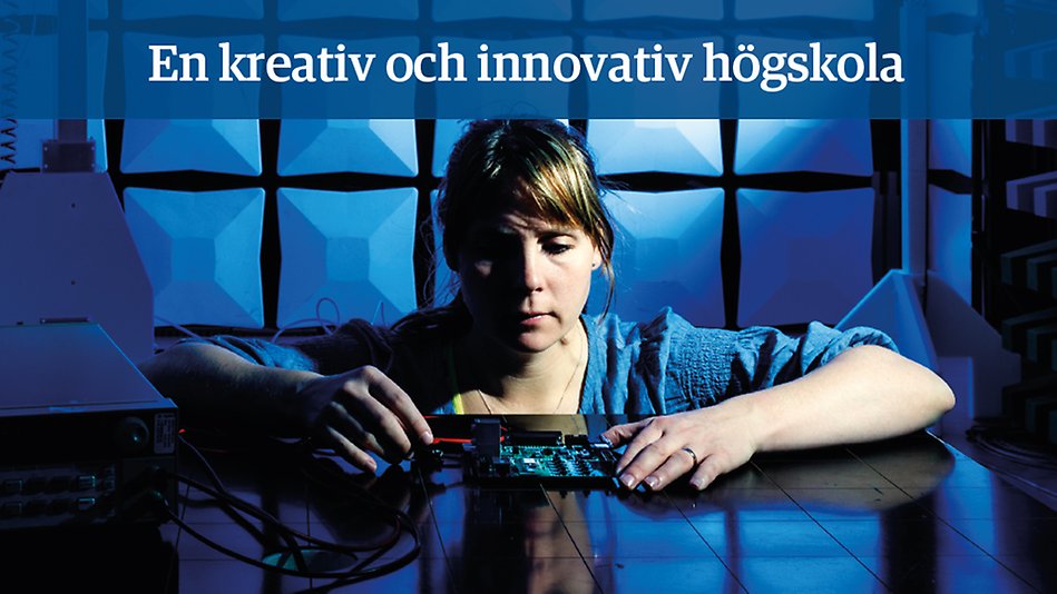 En kvinna sitter med armarna på ett bord och håller i elektronik. Texten "En kreativ och innovativ högskola" på en blå platta. Foto.
