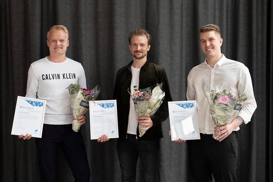 Tre personer som håller upp diplom och blommor. Fotografi.
