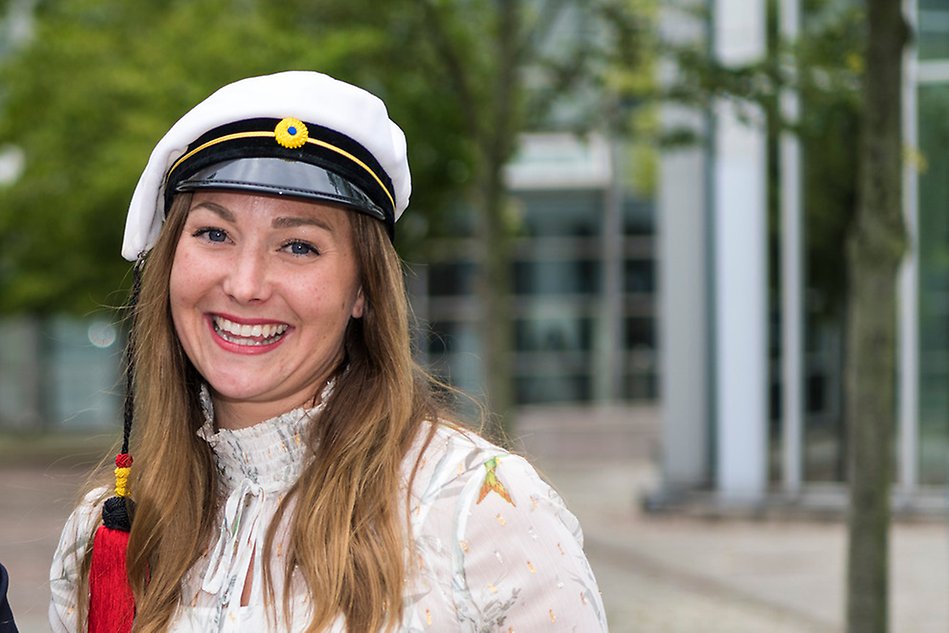 Porträtt av en leende person med studentmössa. Fotografi