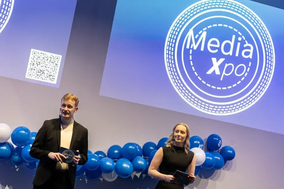 Studenter står på en scen framför publik och pratar. Foto.
