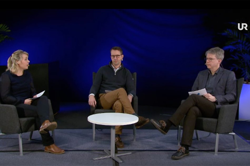 Three people sitting in chairs in a tv studio environment. Photo.