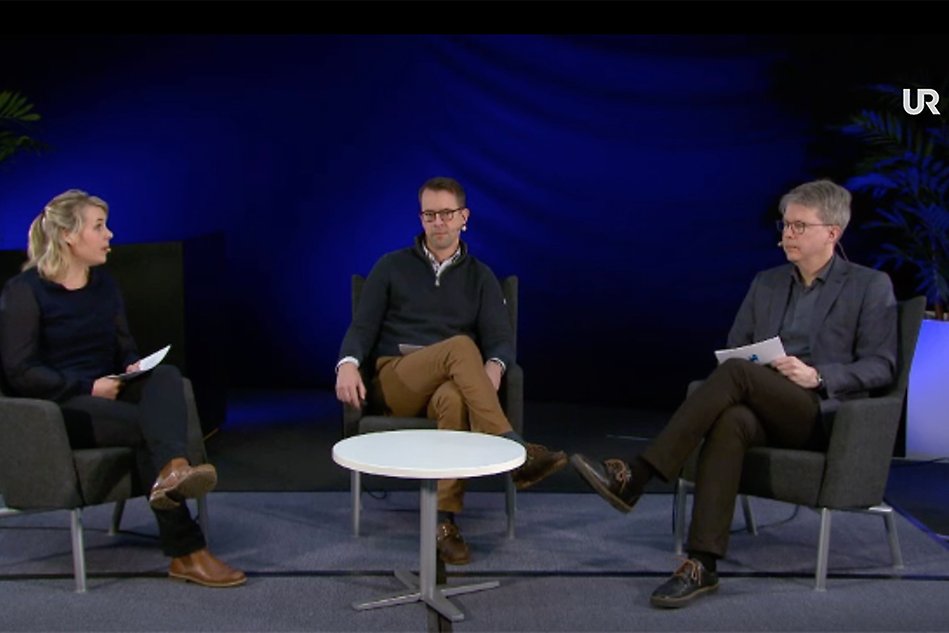 Three people sitting in chairs in a tv studio environment. Photo.