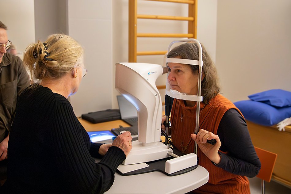 En kvinna undersöker en annan kvinnas syn med hjälp av en ögonkamera.