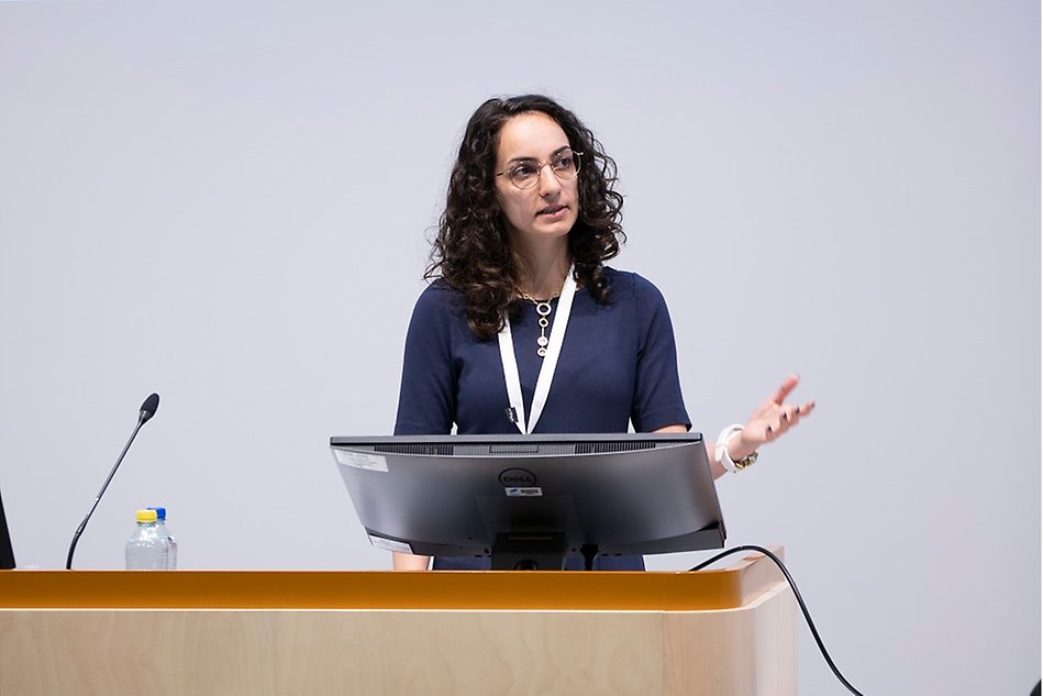 Woman in glasses speaking from behind a lectern.