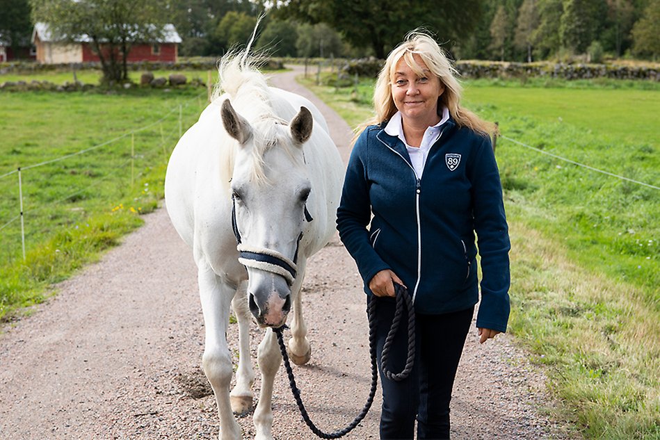 Woman walking alongside a white horse.