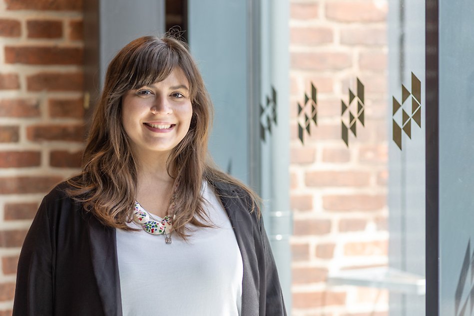 Manoella Antonieta Ramos da Silva is smiling in front of a University building.