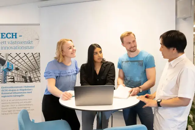 Fyra studenter diskuterar runt ett bord.