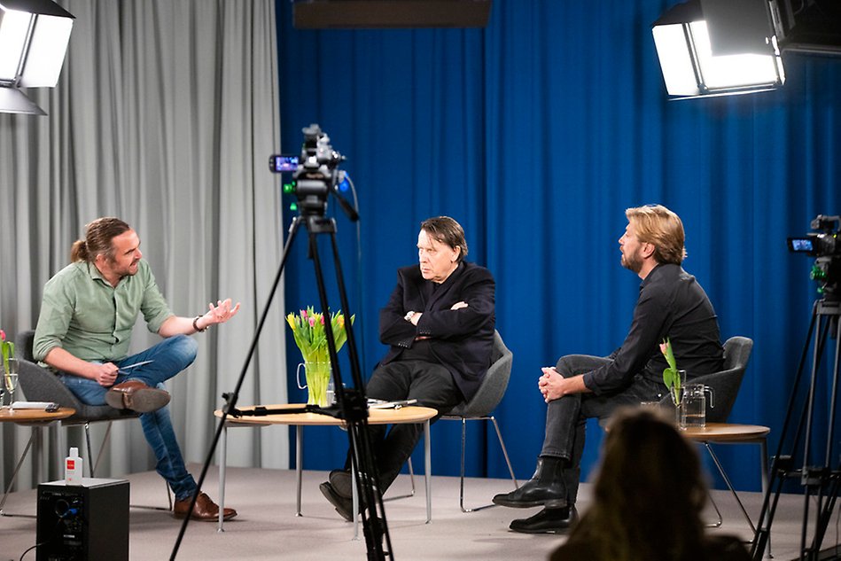 Tre män sitter i fåtöljer i en tv-studio och har ett samtal. Foto.