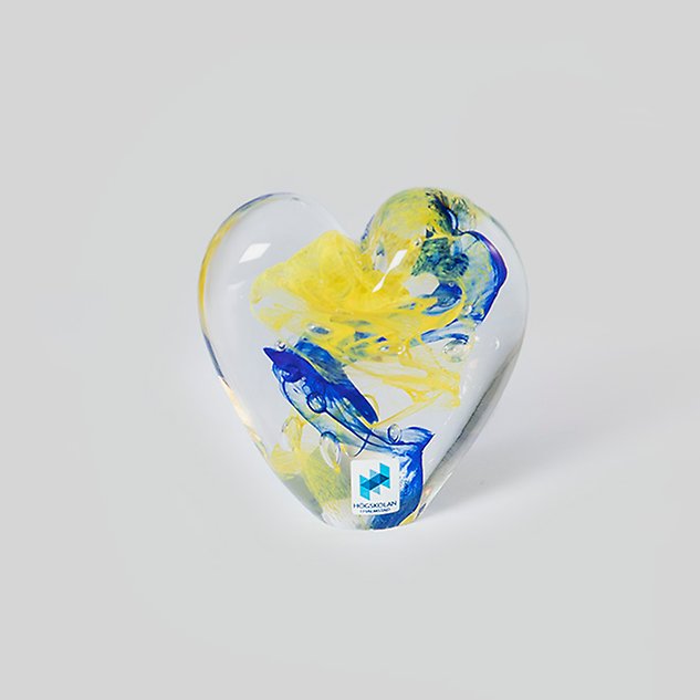 Glaskonst i gult och blått föreställande ett hjärta. Foto.