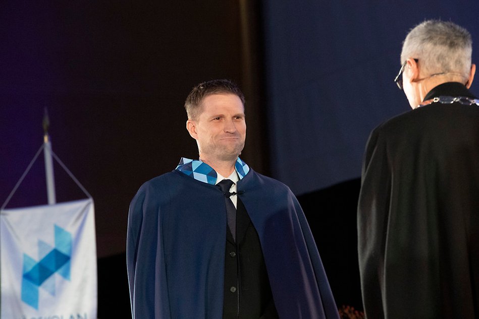 Two men, one wearing a blue robe and one wearing a black. 
