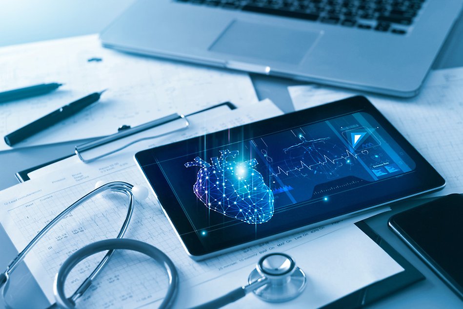 A tablet with healthcare-related symbols on and around it. A stethoscope and a computer are visible.