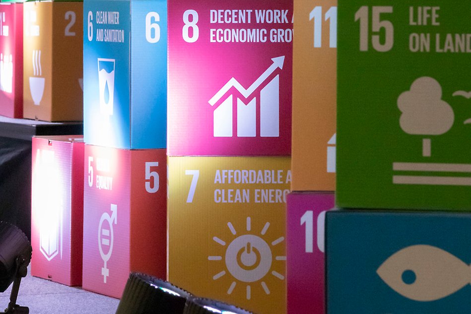 Boxar i kartong i olika färger, föreställande FN:s globala mål för hållbar utveckling, är placerade ovanpå varandra. Foto.