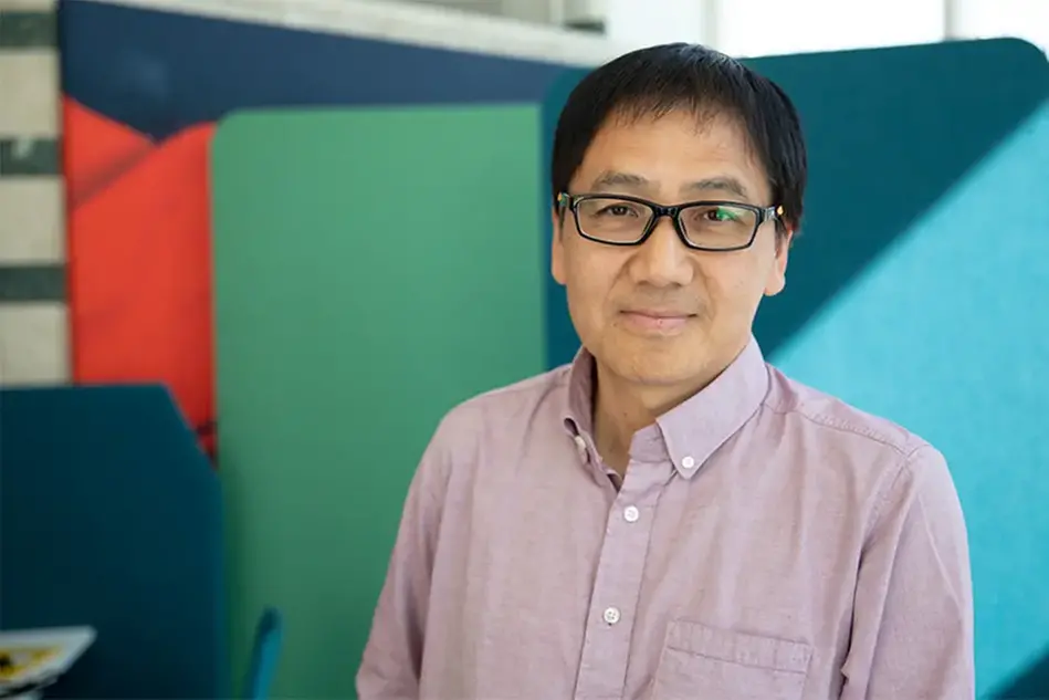 A man with dark hair and glasses looking in the camera. Photo.