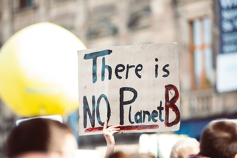 A hand holding up a sign saying ”There is no Planet B”. Photo.