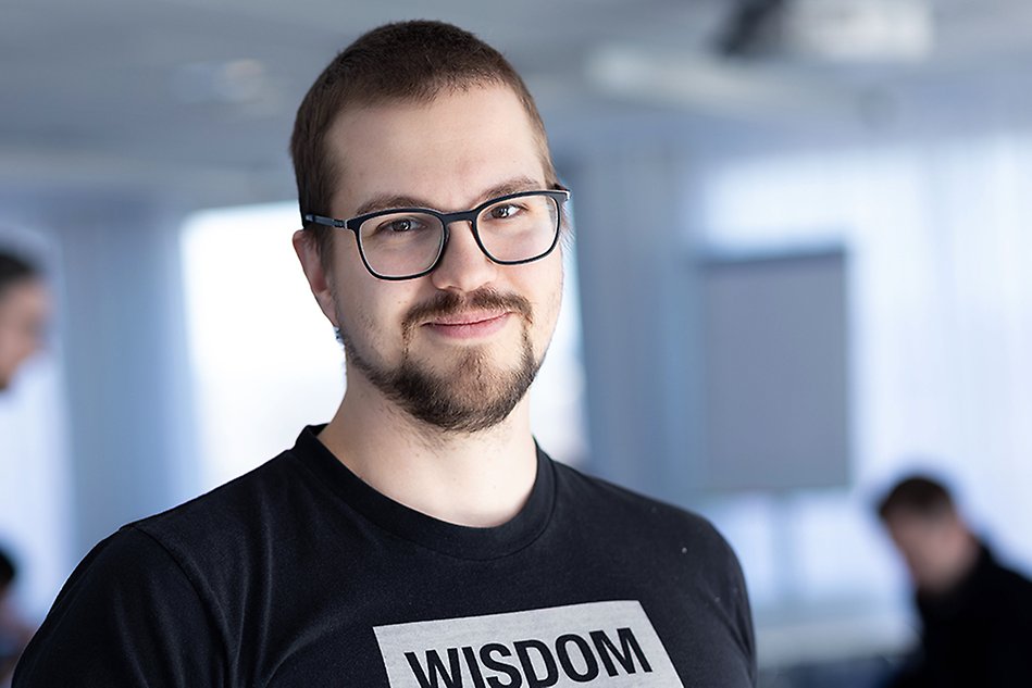 A man with glasses looks into the camera smiling.