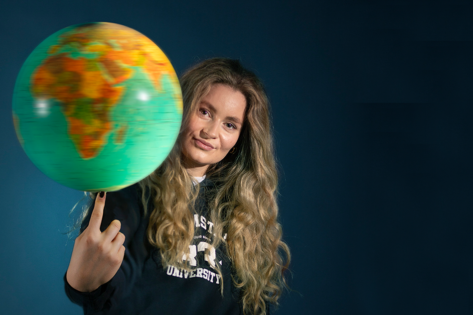 A girl holding a lit up globe in her hand. 