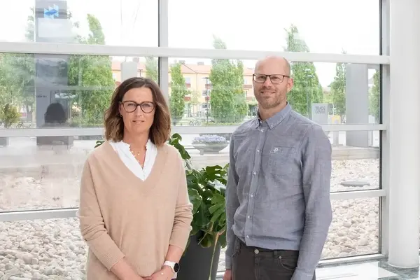 Två personer som står och ler mot kameran