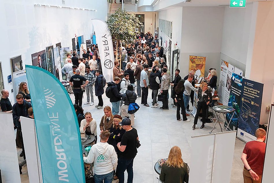 Två personer står och pratar under en mässa. Foto.