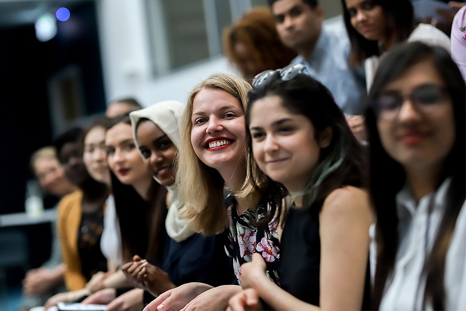 A group of students listening to a lecture, smiling. Photo.