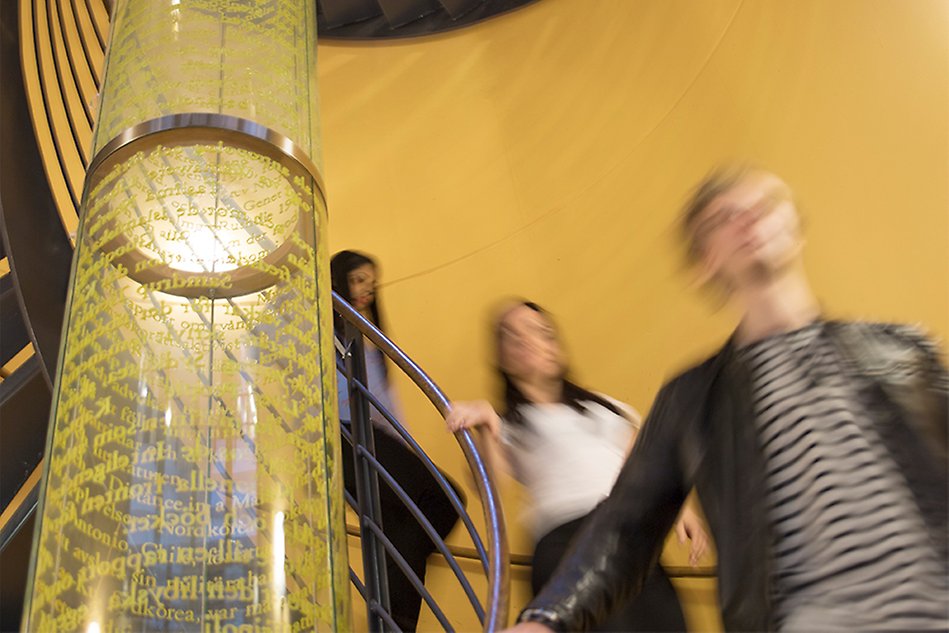 Students going down spiral stairs with artwork in the middle