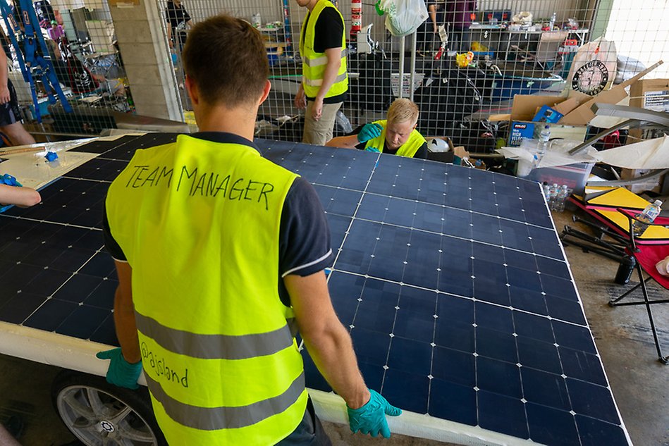 Personer som arbetar med stora solceller. Foto.