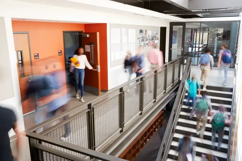 En grupp människor som går upp och ner för en trappa i skolmiljö. Foto