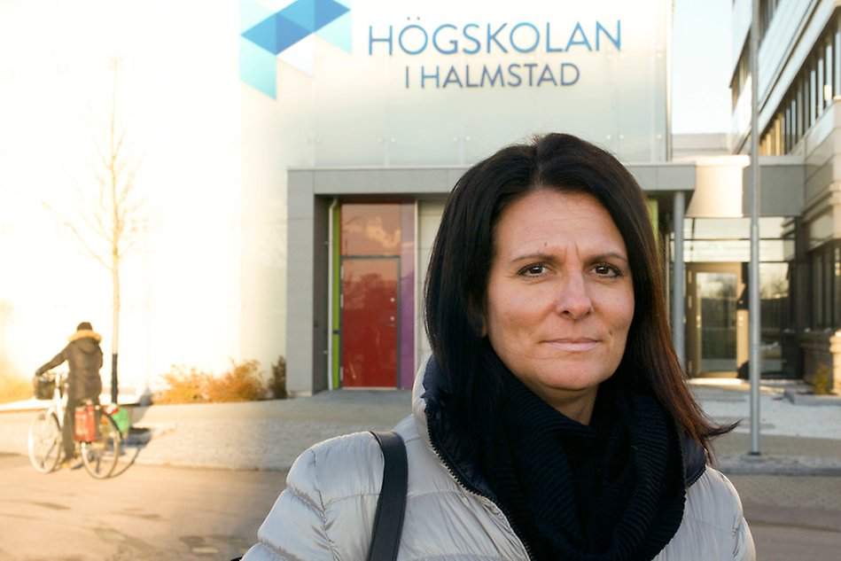 Portrait of a woman in front of a white building with the Halmstad University logo on it