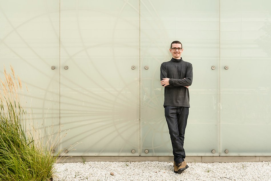 Man leaning against the outside wall of a white glossy building