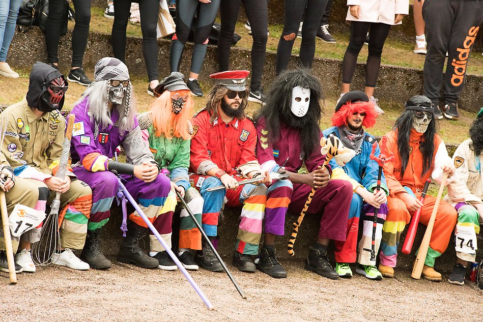 En grupp utklädda studenter, med peruker, masker och färgglada overaller.
